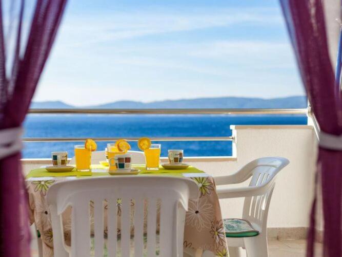 a table with cups and oranges on it with a view of the ocean at Apartments Nena ST - Standard One Bedroom Apartment with Balcony and Sea View A2 in Pisak
