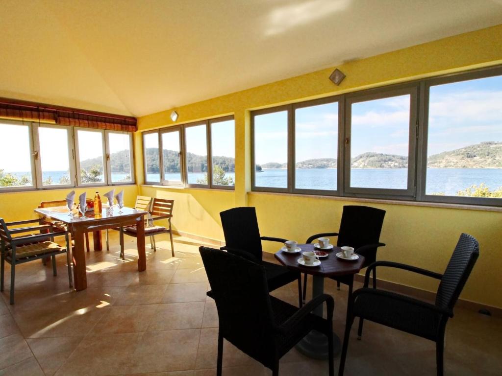 une salle à manger avec tables, chaises et fenêtres dans l'établissement Holiday Home Katica - One Bedroom Holiday Home with Terrace and Sea View, à Vela Luka