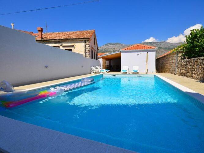 a large blue swimming pool in front of a house at Holiday Home Belmondo- Three Bedroom Home with Terrace and Private Pool A6 in Gruda