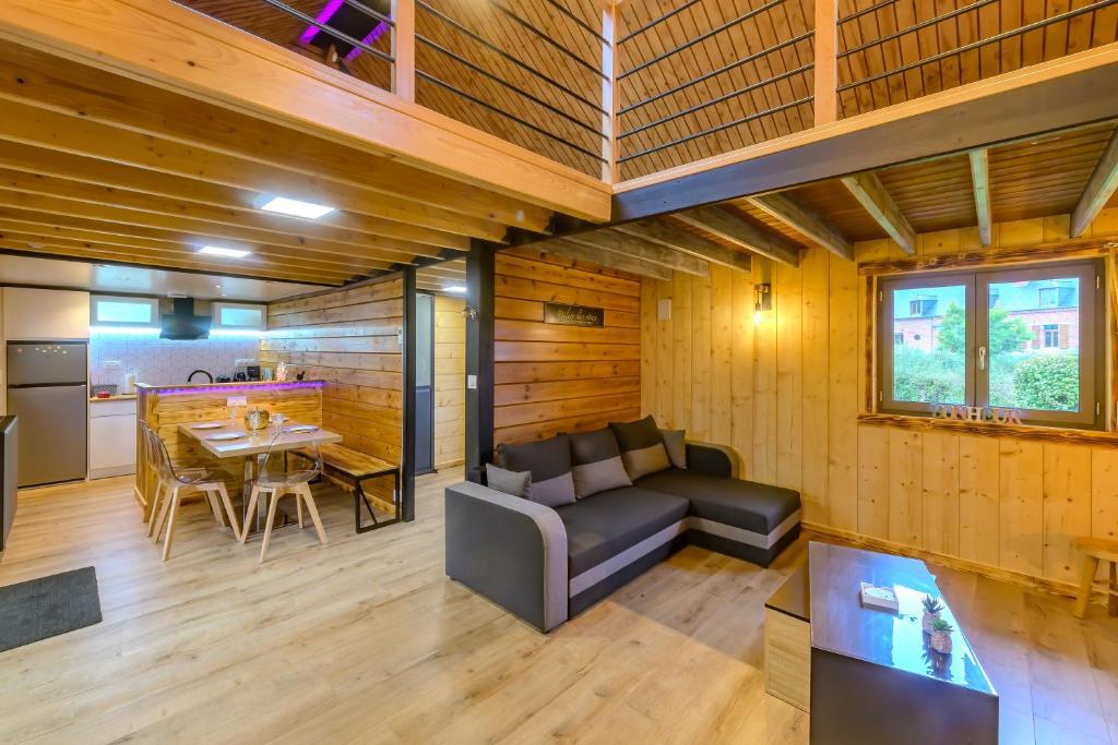 un soggiorno con un divano e un tavolo di Rêves au Chalet - Maisonnette avec jacuzzi a Floyon