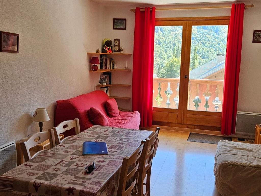 une salle à manger avec une table et des rideaux rouges dans l'établissement Charmant Studio Cabine 4 Pers, Exposé Sud, Balcon, Piscine, Parking, Proche Pistes et Commerces - FR-1-263-144, à Valloire