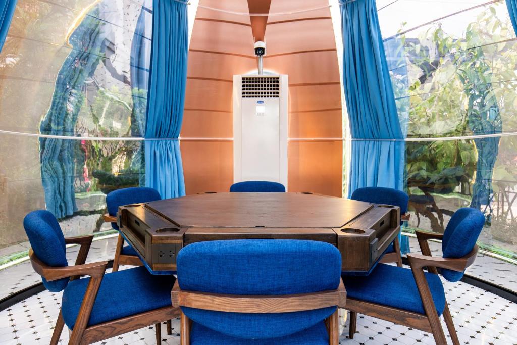 A compact glass-walled meeting room with a round table and blue chairs.
