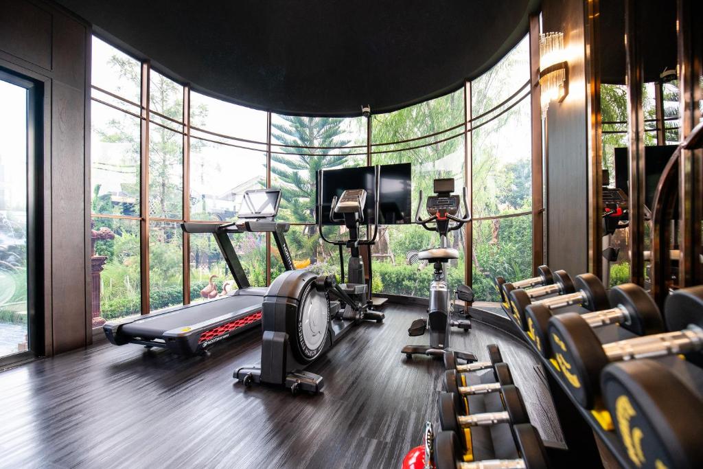 A bright fitness room with cardio machines and a dumbbell rack beside curved windows.