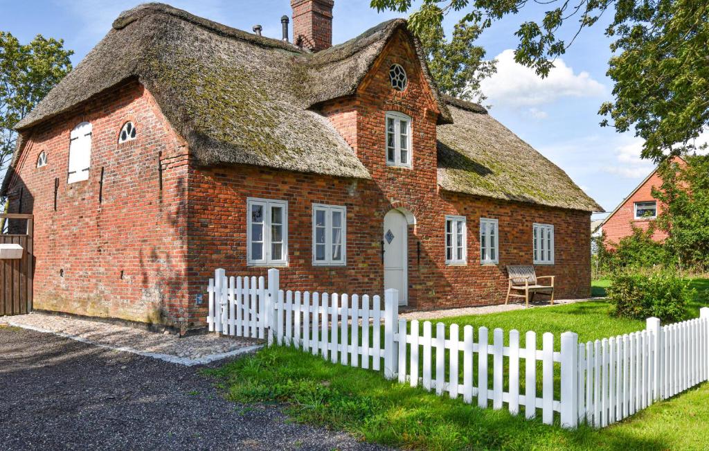 una vieja casa de ladrillo con una valla blanca en Nice Home In Emmelsbüll Horsbüll, en Emmelsbüll-Horsbüll