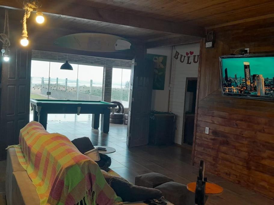 a person laying on a couch in a living room with a pool table at Casa BuLuMAR in Conventos