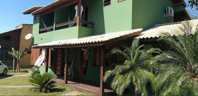 a green building with palm trees in front of it at SunHouse Praia do Rosa in Praia do Rosa