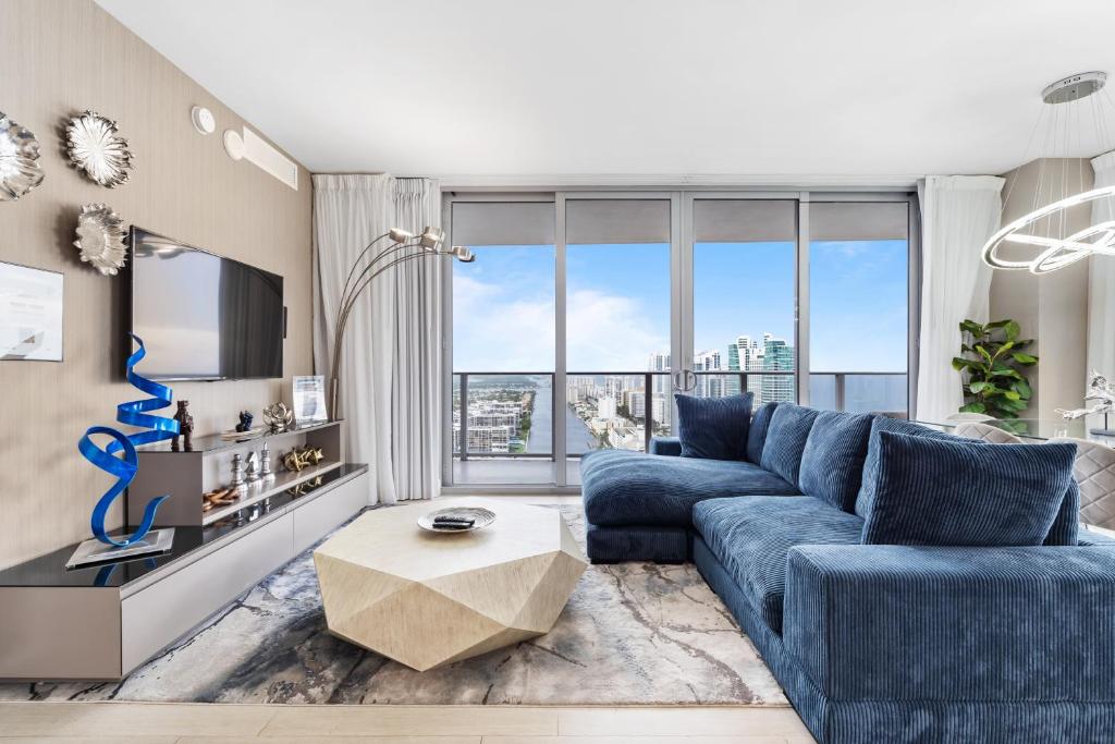 a living room with a blue couch and a large window at Hyde Beach House - 2BD-2BA MANSION WITH DIRECT OCEAN VIEW, Resort Amenities, Rooftop Pool and Hot tub, Tennis court, few min walk to the ocean in Hollywood
