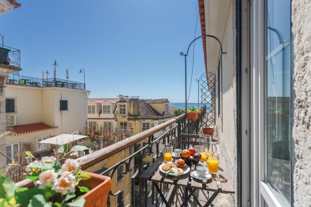 a balcony with a table with food and drinks on it at Baixa Chiado LUXURY BEDROOMS in Lisbon