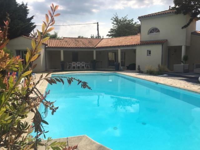 une grande piscine bleue devant une maison dans l'établissement VILLA Meschers sur Gironde, à Meschers-sur-Gironde