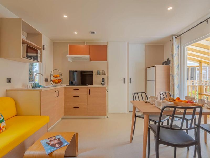 a kitchen and living room with a table and chairs at Camping Les Grenettes in Sainte-Marie-de-Ré
