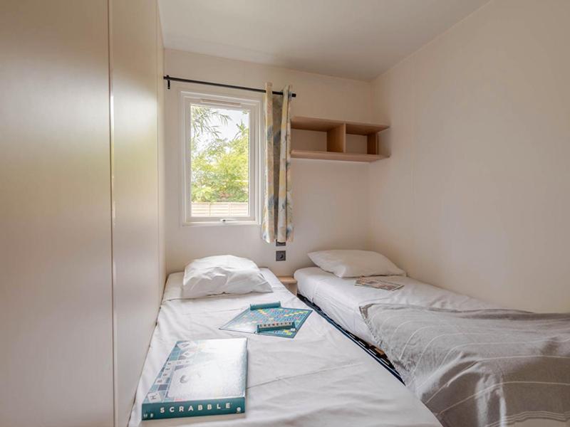 two twin beds in a room with a window at Camping Les Grenettes in Sainte-Marie-de-Ré