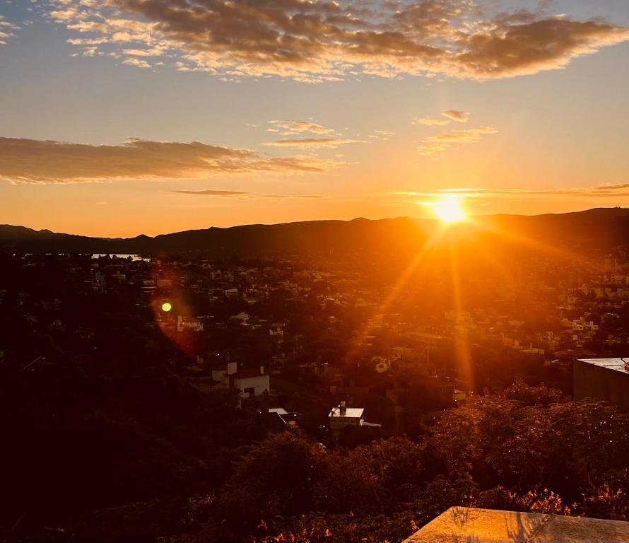 a sunset with the sun setting over a city at Amanecer Serrano Carlos Paz in Villa Carlos Paz