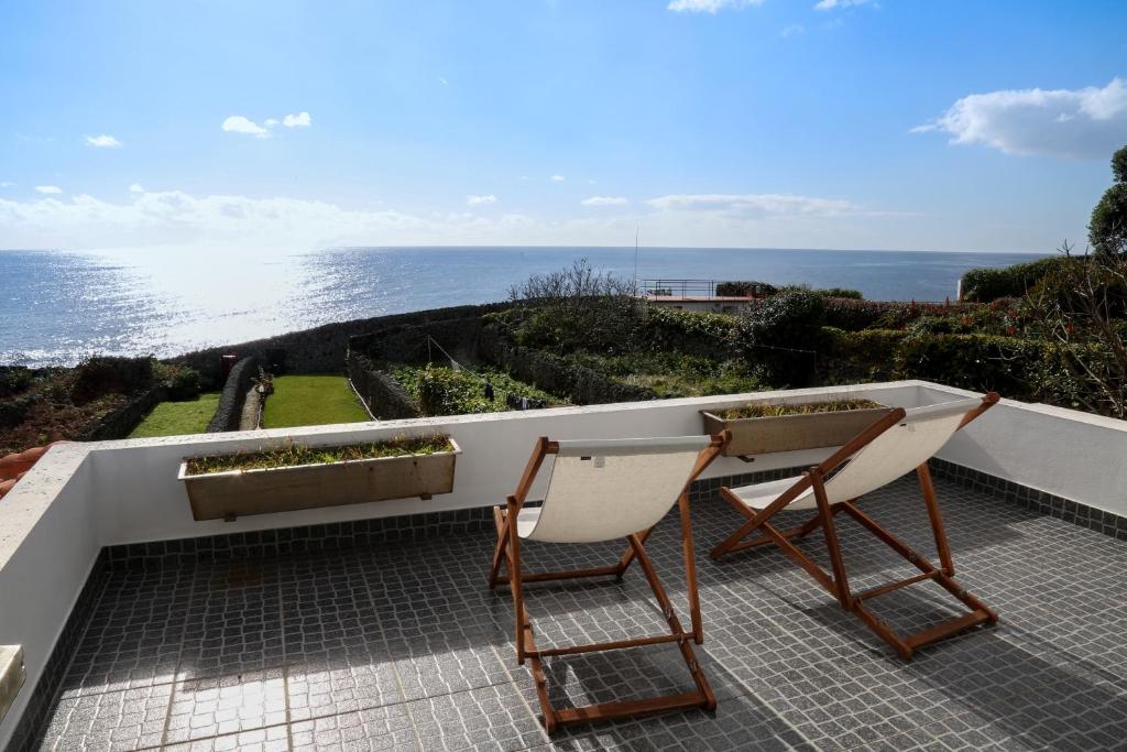 two chairs and a table on a balcony with the ocean at Casa Do Atlântico in Rosário-Lagoa