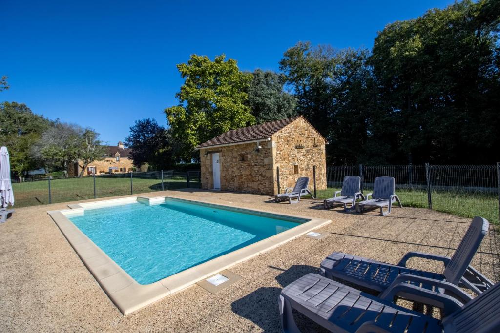 ein Pool mit zwei Stühlen und ein Gebäude in der Unterkunft Le Grand Pech in Le Sirey