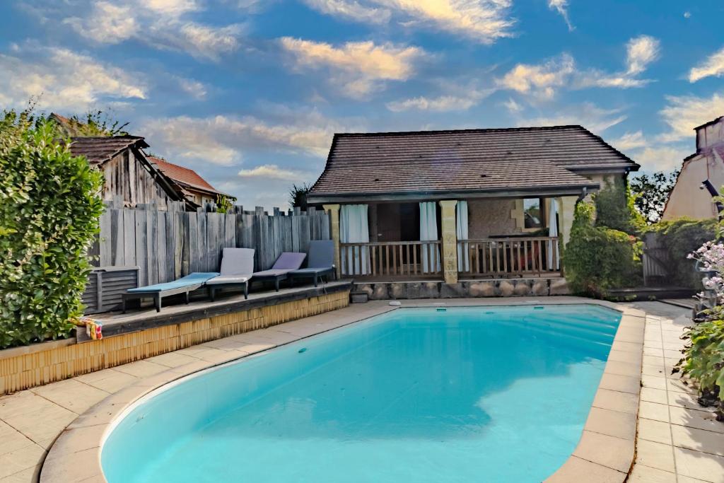 una piscina con dos sillas y una casa en La Gourmandise d'Huguette, en Beynac-et-Cazenac