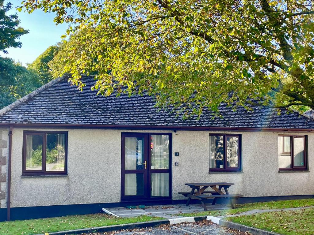 a house with a picnic table in front of it at 2 Bed Lodge - Sleeps 4 - Pets - Pool - Garden in Penzance