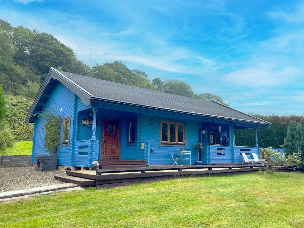 a blue house with a porch in a yard at Sky Lodge Great Ayton Yorkshire in Great Ayton