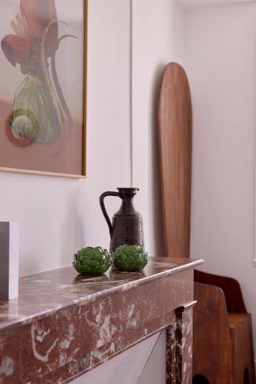 une table avec un vase et deux légumes verts sur elle dans l'établissement La maison de Crèvecoeur, à La Croix-Saint-Leufroy