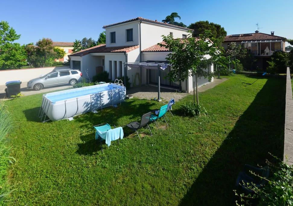 une cour avec une piscine et un bateau dans l'herbe dans l'établissement Maison Spacieuse Climatisée avec Jardin 2 PKG et Piscine, à Aucamville