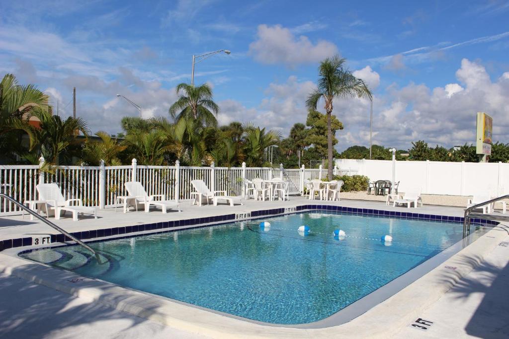 a swimming pool with white chairs and a white fence at Sunshine Inn & Suites Venice, Florida in Venice