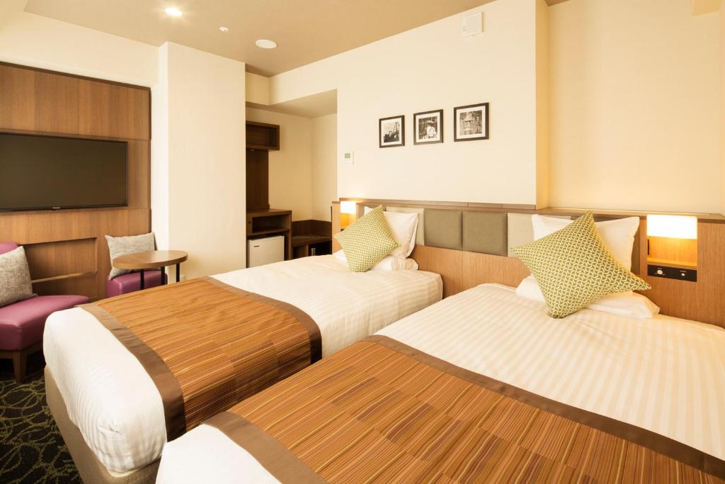 a hotel room with two beds and a television at Hotel Mystays Gotanda Station in Tokyo