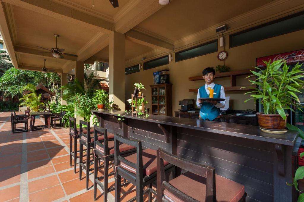 a man standing behind a bar in a restaurant at Prince Angkor Hotel & Spa in Siem Reap