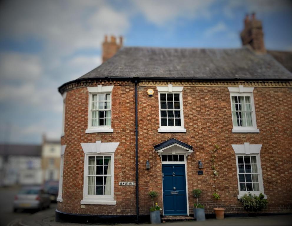 dom z czerwonej cegły z niebieskimi drzwiami w obiekcie The Corner House w mieście Shipston-on-Stour