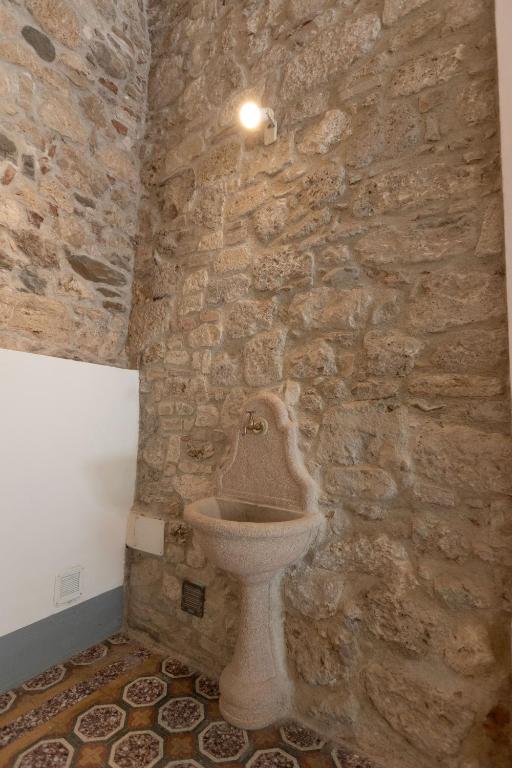e bagno in pietra con servizi igienici in un muro di pietra. di Palazzo Antico ad Ascoli Piceno