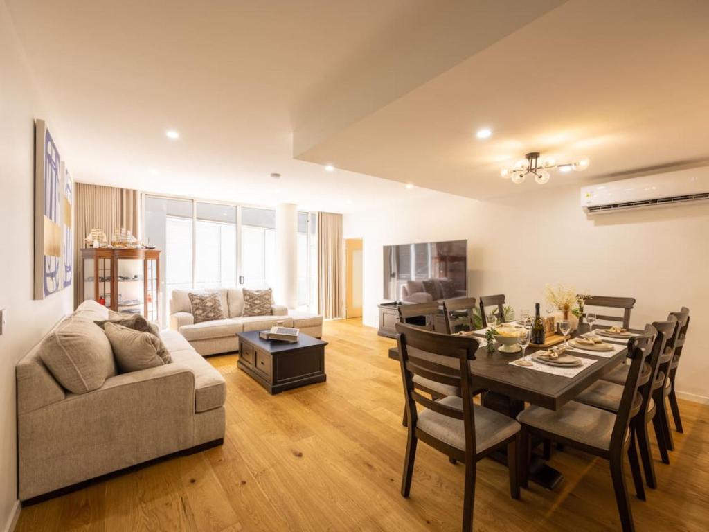 Una sala de estar con una mesa y un comedor. en Luxury 4BR Cozy Home Pool, Gym, Sauna, wParking at CBD, en Brisbane