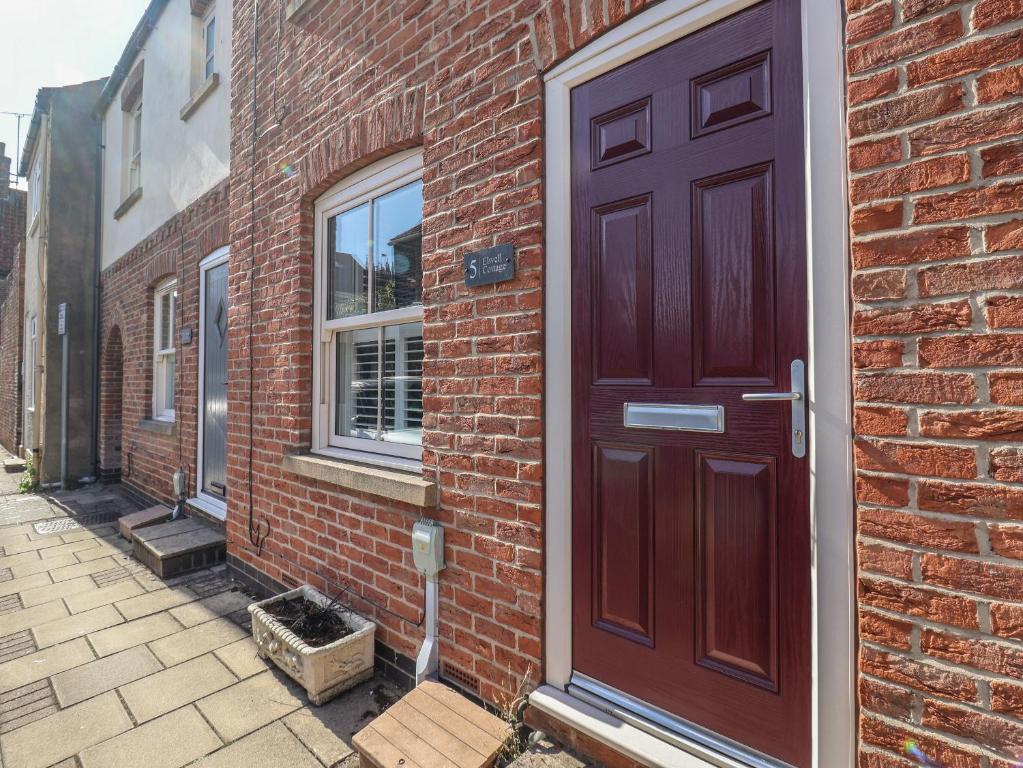 a brick building with a brown door on the side of it at Elwell Cottage in Beverley
