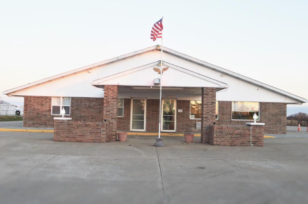 a brick building with an american flag on top at Night Inn in Sweet Springs