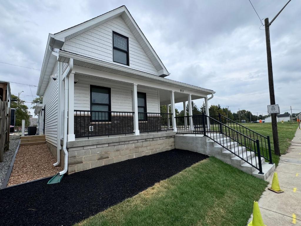 a white house with a porch with a fence at Evans-Clark Manor in Indianapolis