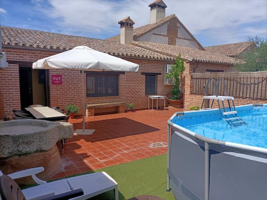 a backyard with a swimming pool and an umbrella at MUSEUM La Almazara de Alcabón 11th century in Alcabón