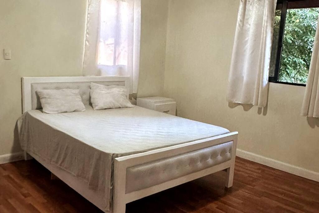 a white bed in a bedroom with a window at Escapada en las Montañas in Jarabacoa