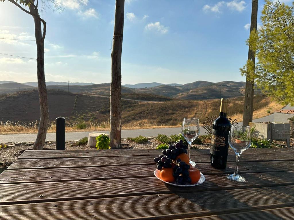 a plate of fruit and wine glasses on a wooden table at Casa dos Avós in Estorninhos