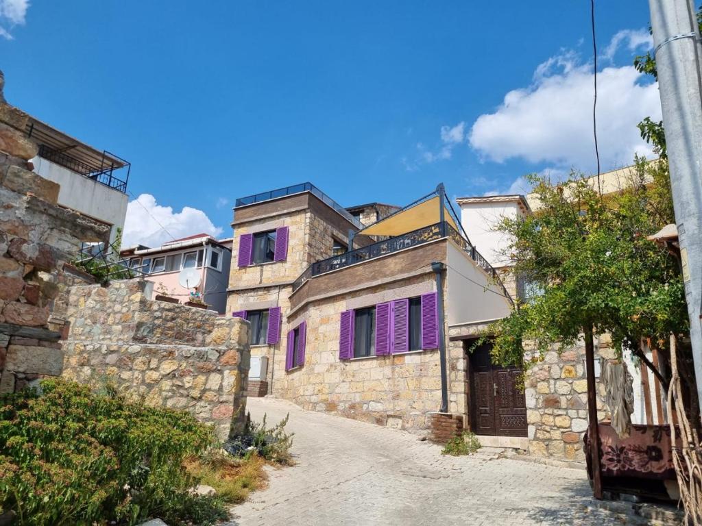 a group of houses with purple windows on a street at İncirci Stone House, Sazlı Köyü in Ayvacık
