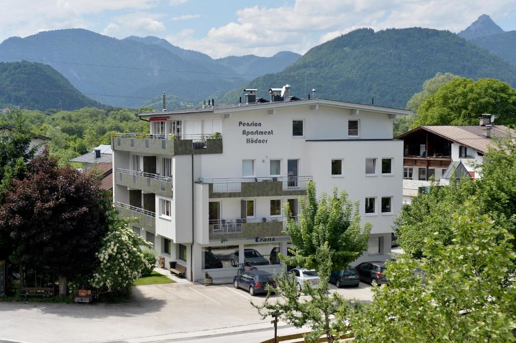 a large white building with mountains in the background at Pension Apartment Hödner in Ebbs