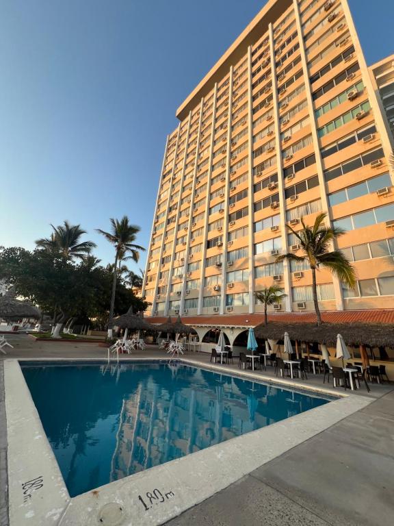 a hotel with a swimming pool in front of a building at Islas del Sol in Mazatlán