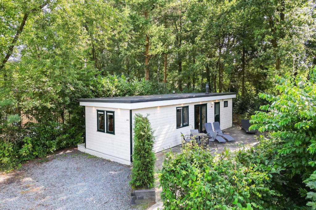 a white tiny house in the woods at H15, Sauna- en Wellnesschalet geschikt voor 2 personen in Epe