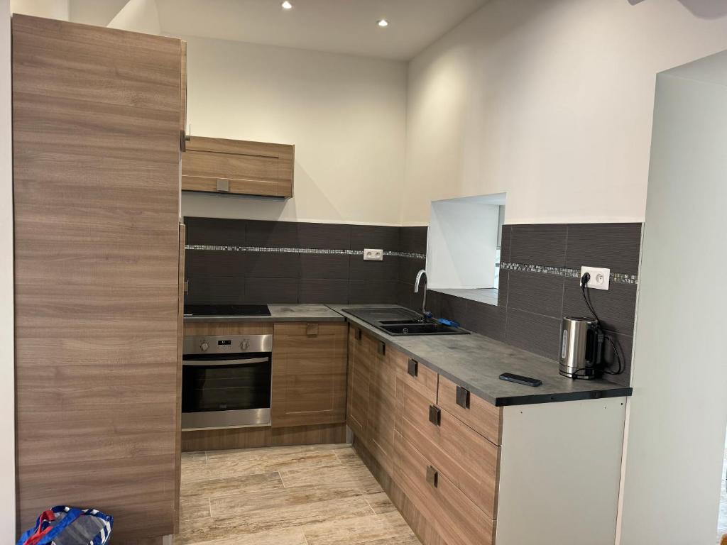 une cuisine avec des armoires en bois et un réfrigérateur blanc dans l'établissement Gîte gina, à Grand-Fort-Philippe