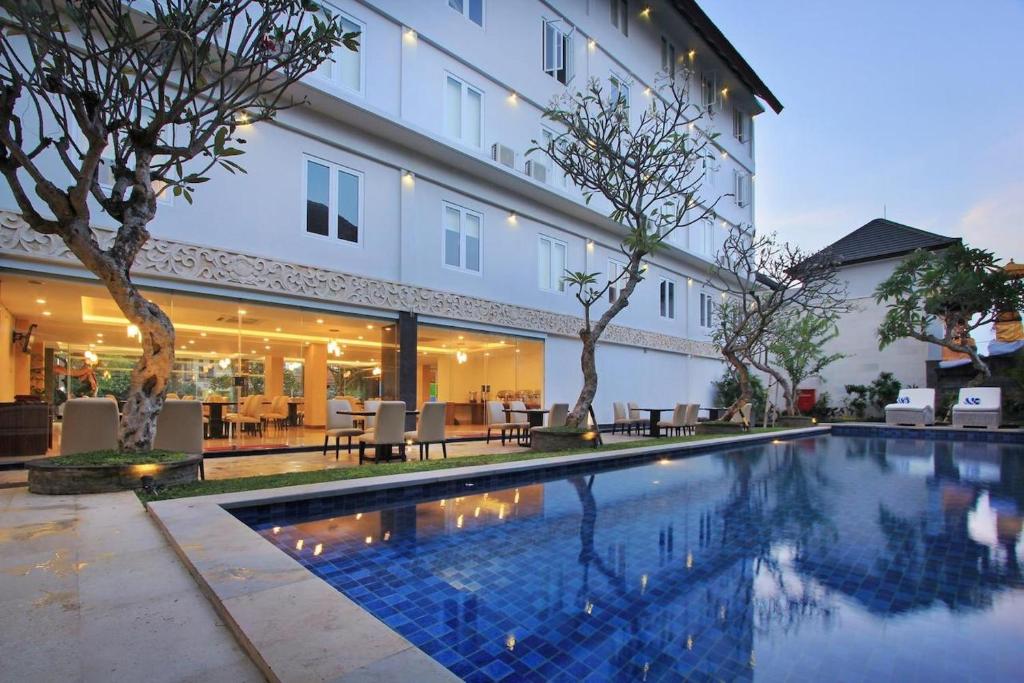 a swimming pool in front of a building at Mars City Hotel in Denpasar