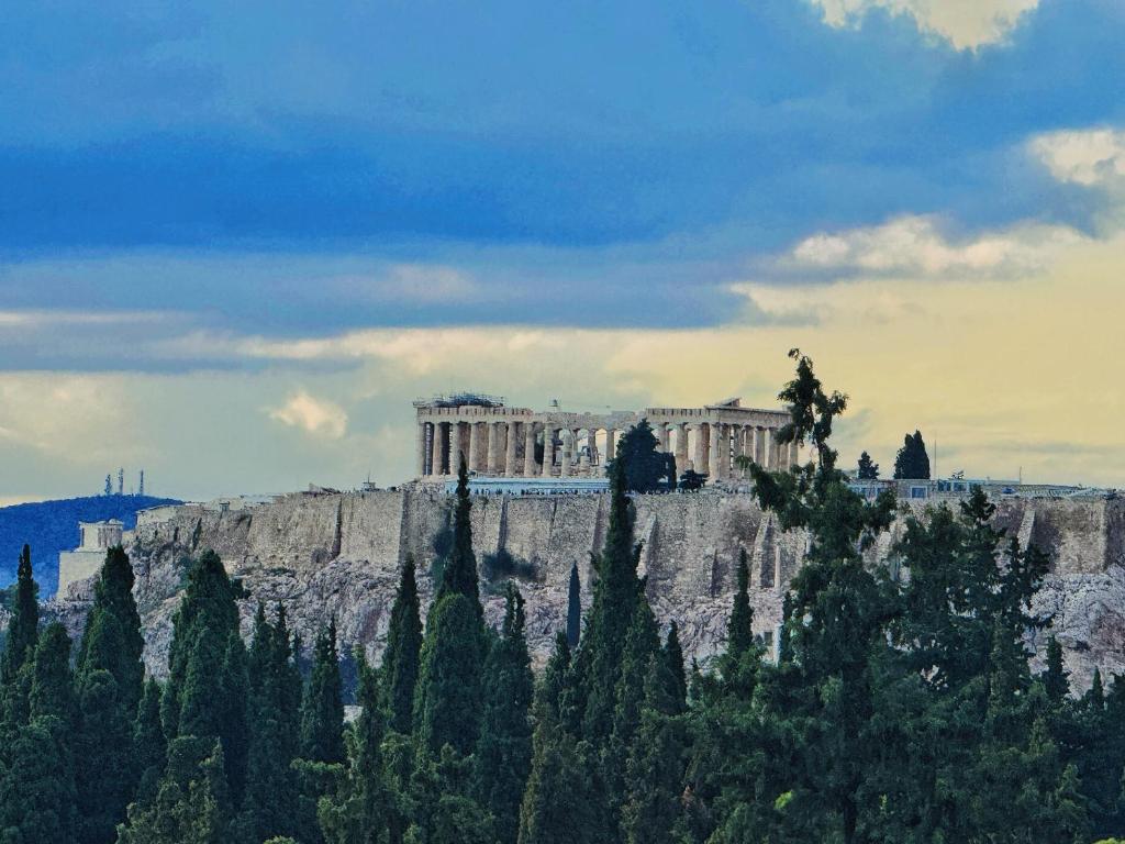 um edifício no topo de uma montanha com árvores em Acropolis view em Atenas