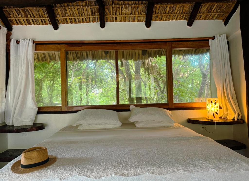 Un dormitorio con una cama grande con una ventana grande. en Black Sand Hotel Boutique, en Zapotal