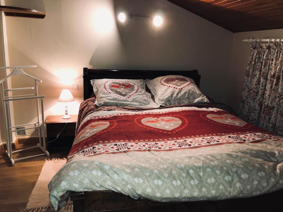 a bedroom with a bed with heart pillows on it at Appartement 2 chambres avec terrasse in Polliat