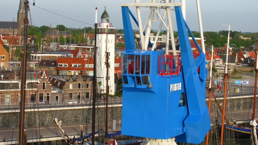 een blauwe boot is aangemeerd in een haven bij Havenkraan van Harlingen in Harlingen