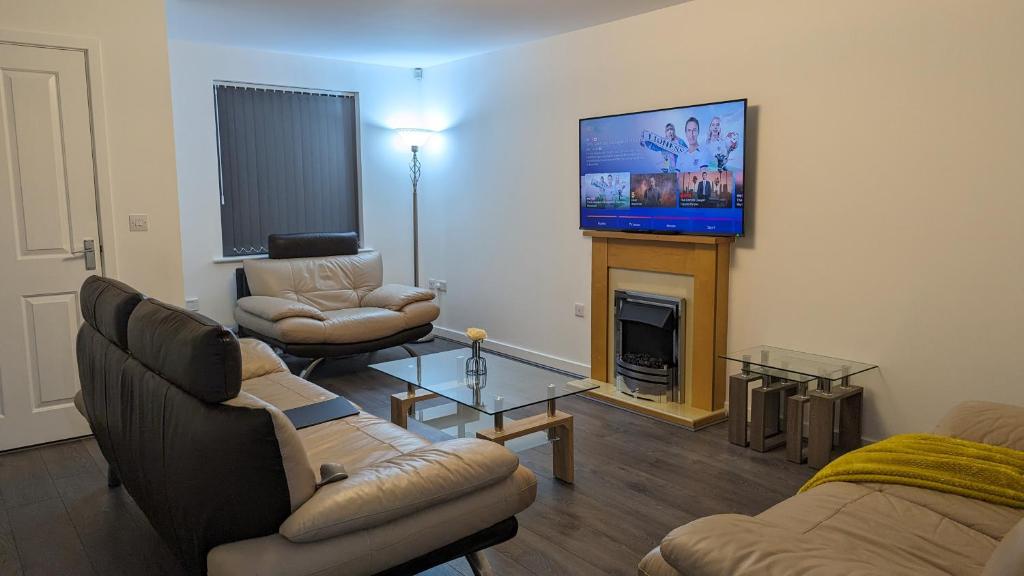un soggiorno con divani, TV e camino di CLARITURF - 4 Bedroom Semi - Private Parking near Turf Moor, Town Centre, Transport and Motorway Links next to Canal, 3 Parks and Lake - Sky and Netflix a Burnley