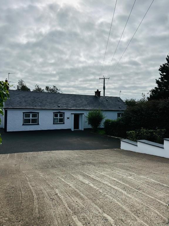 a white house with a driveway in front of it at Cloyfin Holiday Home in Cloyfin