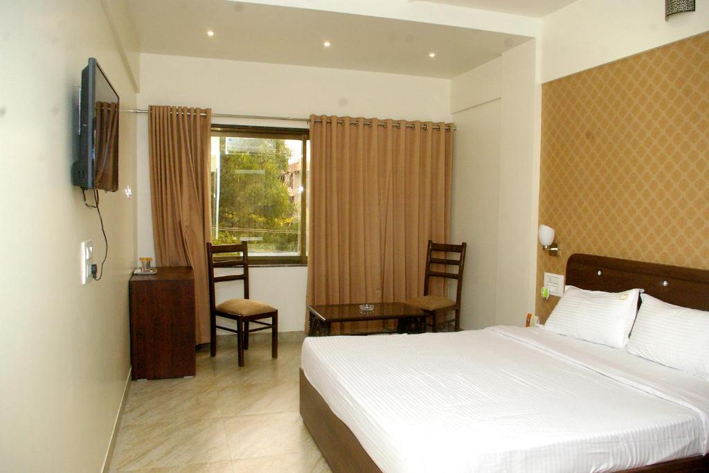 a bedroom with a bed and a desk and a window at Hotel Gulmohar Pride in Ahmadnagar