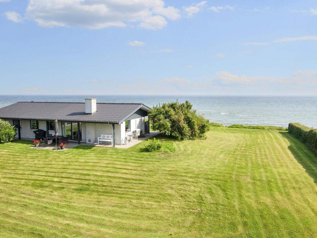 una casa su un campo con l'oceano sullo sfondo di Seaside Panorama Retreat - By Traum Ferienwohnungen a Odder
