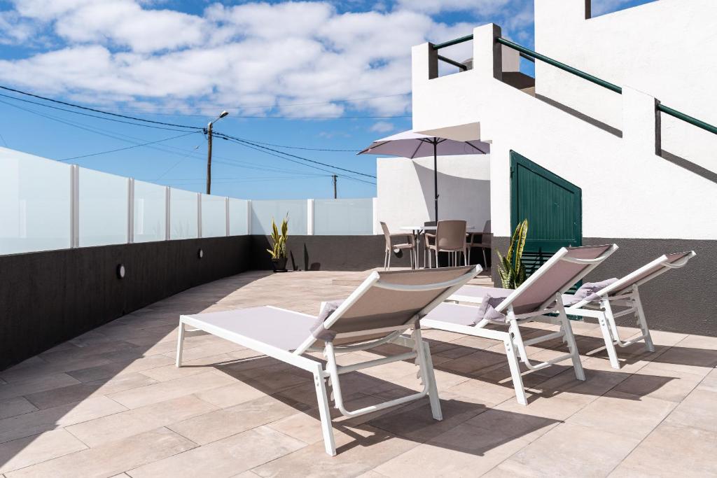 a patio with chairs and an umbrella on a roof at Atouguia House - Traditional House in Calheta